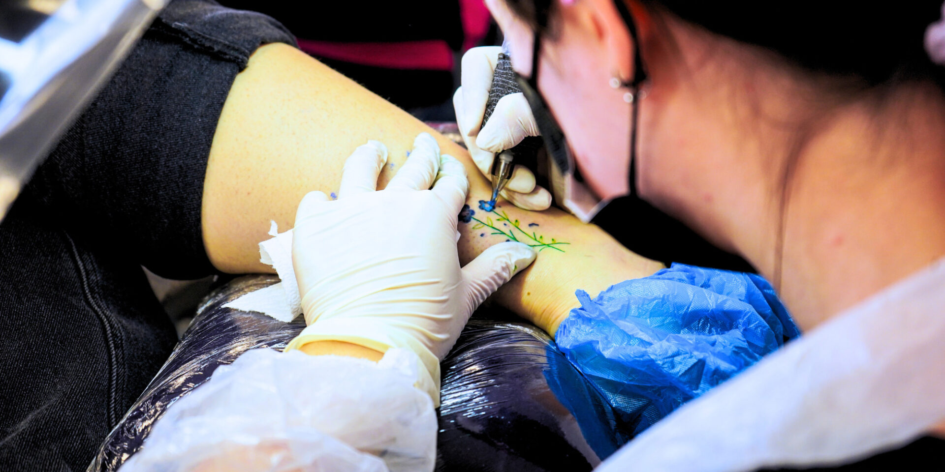 Professional performing a painterly tattoo on a client