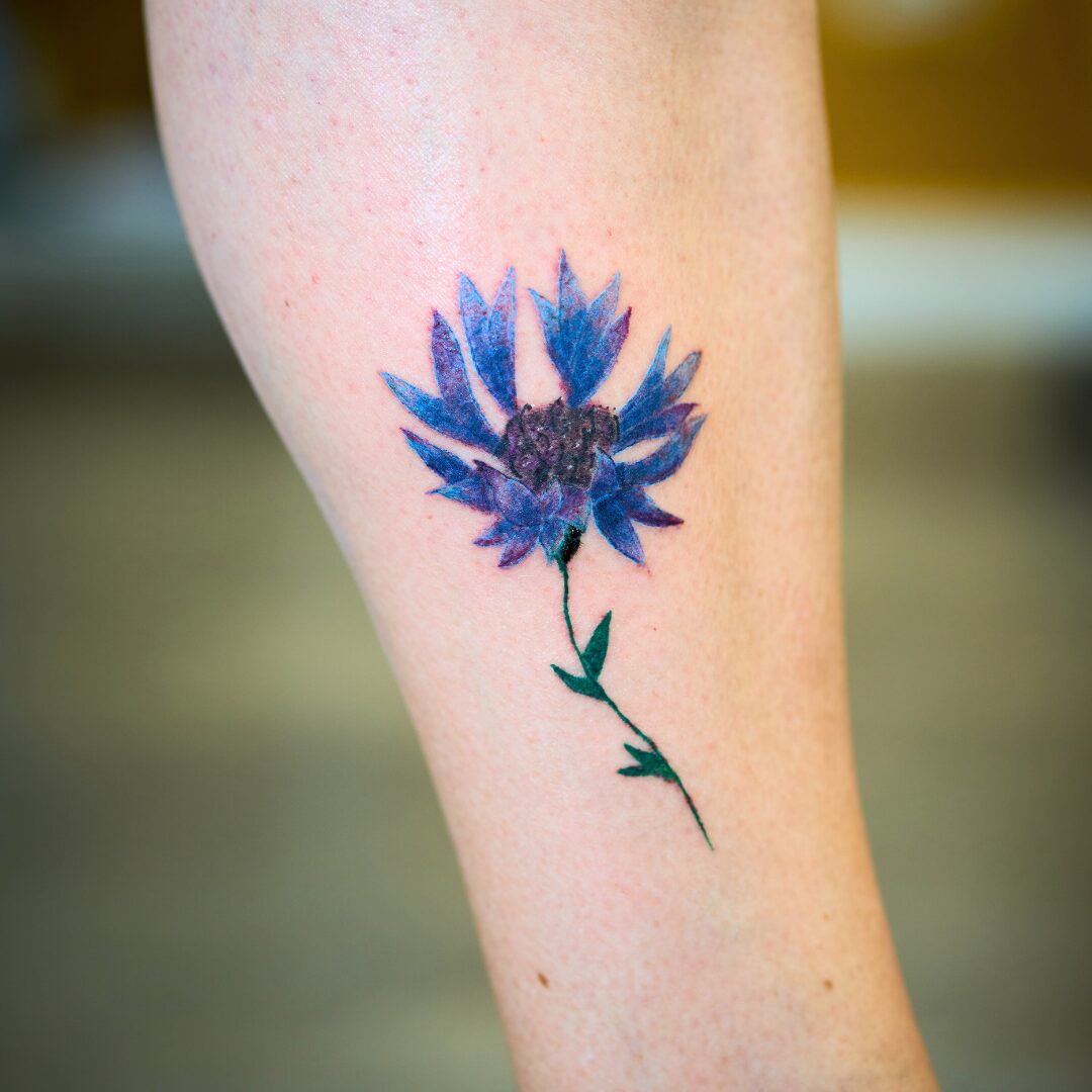 Painterly style flower tattoo on the calf